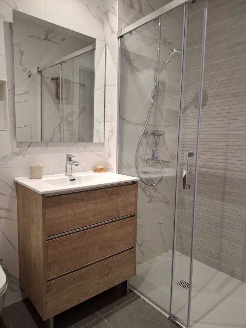 Baño con ducha y lavabo con mueble de madera