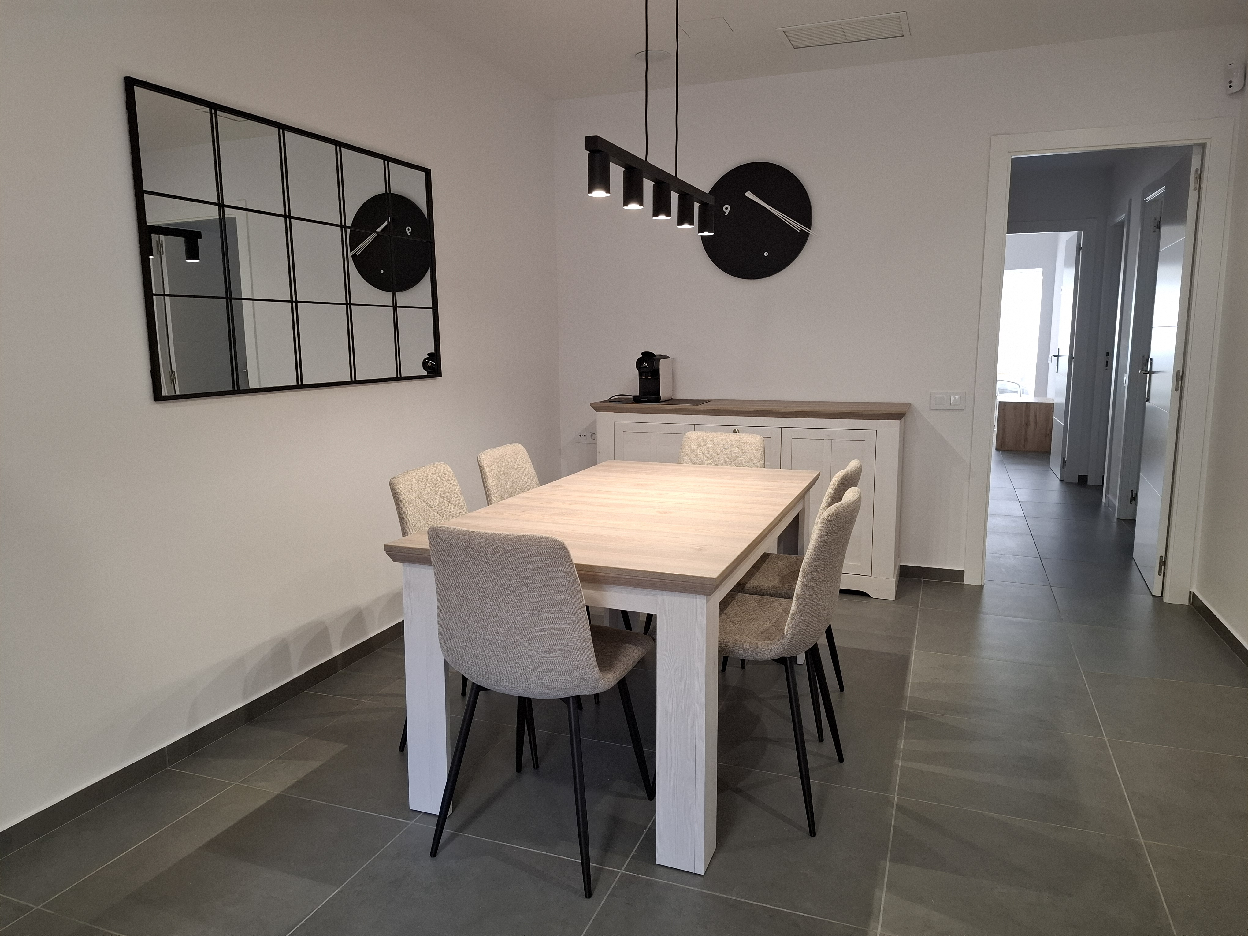 Comedor con mesa de madera, espejo y reloj de pared